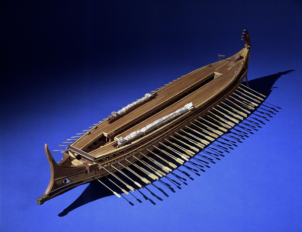 Modello di trireme. Modello di Aristoteles e George Rallis. La trireme era la nave da guerra che portò Atene alla preminenza nelle acque greche nel V e IV secolo a.C. La nave era progettata per essere veloce, leggera e facile da manovrare. Con i tre ordini di rematori che danno il nome alla trireme, la nave agiva come un ariete azionato dai remi e manovrato da rematori altamente addestrati e disciplinati.