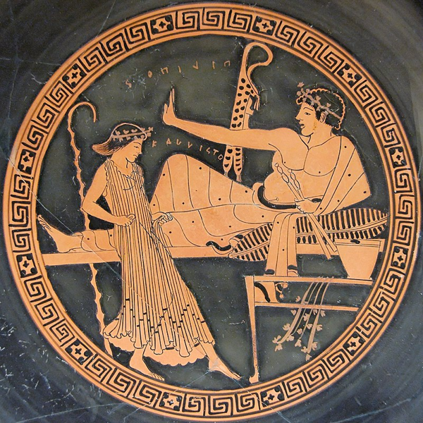 Interno di una kylix attica a figure rosse del Pittore di Brigos (British Museum): una giovane prostituta (hetera) danza davanti a un ospite che regge un aulos. Un'iscrizione, in parte sopra la mano del simposiasta e in parte sotto, recita: "PILIPOS KALLISTO" ("Filippo è il più bello").